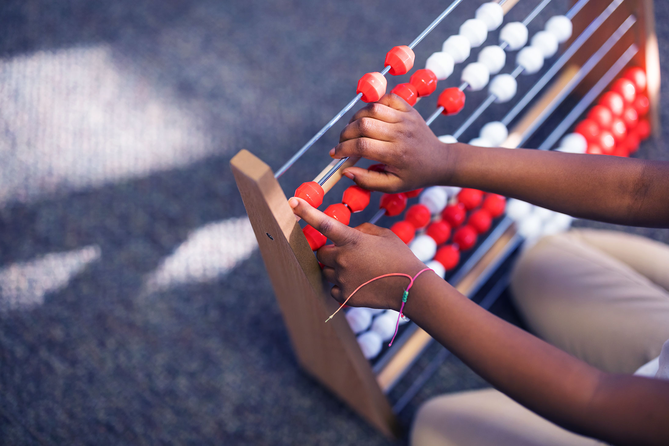 Closeup of student's hands using an abacus in the classroom.