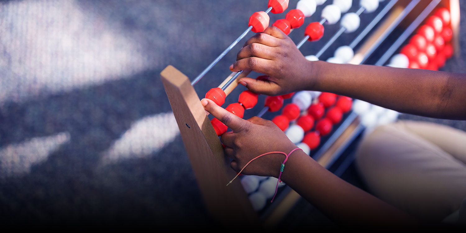 Closeup of student's hands using an abacus in the classroom.