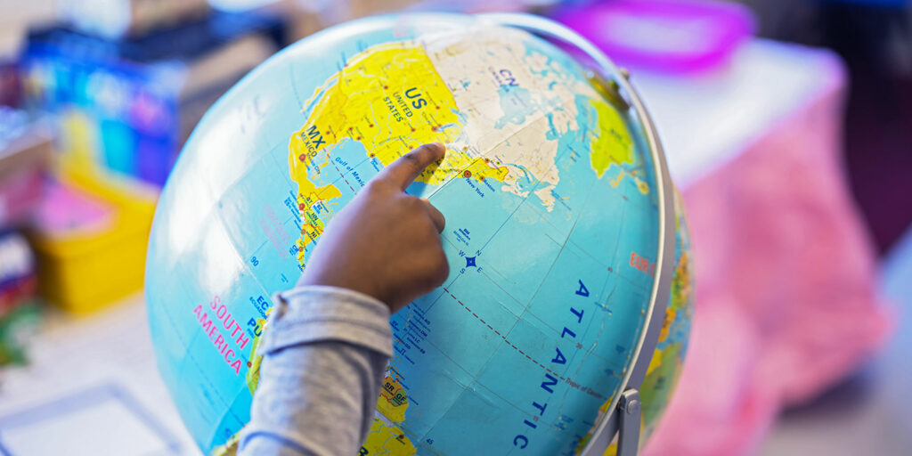 Close up of student's hand pointing to Ohio on a globe.